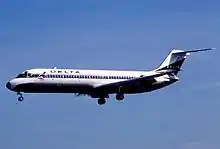 A midsized white twin-engine passenger jet in the air with landing gear deployed