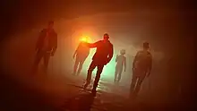 Three members of Down with Webster walking under orange lightning with three members following behind.