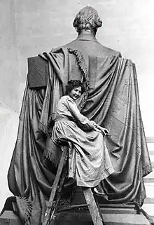 Elsie Ward sitting atop a ladder as she works on the backside of the Seated Lincoln.