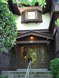 Photograph of the Bowman Apartments, showing a building entry set in a recess of a two-story building with broad, overhanging eaves