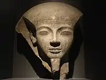 Part of a smiling head sculpted in dark grey rock