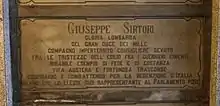 A marble gravestone on the wall of a crypt