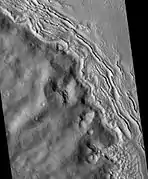 Hecates Tholus ridges, as seen by HiRISE. Ridges are to the west-northwest of Hecates Tholus. It has been proposed that this region was affected by a volcanic eruption that occurred under a 200 meter-thick ice sheet.