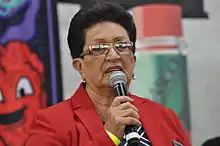 Picture of Marie Sharp in red jacket proudly holding microphone receiving Hall of Fame award