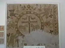 Mosaic on a wall with four figures in the corners and a large cross in the middle
