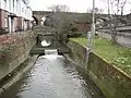 River Brent at Brent Cross. The Ordnance Survey 1:50,000 scale mapping shows a sea of dark green here as the A406 North Circular Road and the A41 Hendon Way meet at the Brent Cross Flyover. A small weir impounds a head of water as the river flows down towards the Brent Reservoir.