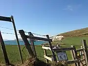 Skewing in a photograph taken from a car moving at 80&nbsp;km/h (50&nbsp;mph). Objects in the foreground, such as the fence and gate, have become skewed, while more distant objects in the background, such as the cliff, remain as normal.