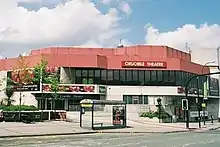 an exterior shot of a threatre with a red roof