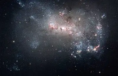 Image 3NGC 4449Photograph: NASA, ESA, A. Aloisi (STScI/ESA), and The Hubble Heritage (STScI/AURA)-ESA/Hubble CollaborationAn image of NGC 4449, highlighting its qualities as a starburst galaxy. NGC 4449, an irregular galaxy in the constellation Canes Venatici located about 12 million light years from Earth, has a rate of star formation twice that of the Milky Way's satellite galaxy, the Large Magellanic Cloud. Interactions with nearby galaxies are thought to have influenced this star formation.More selected pictures