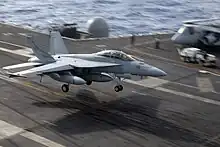 Jet aircraft with landing gear extended flying in a nose-high attitude.