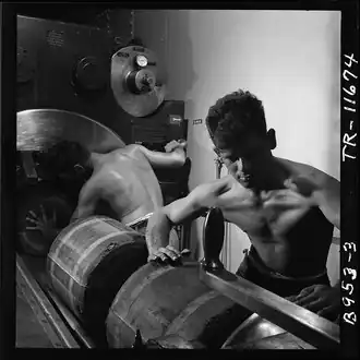 Barbette of 16" gun on board the USS New Jersey (BB-62). Gunners packing in bags of powder which will fire the huge shell already in gun. [Nov 1944]